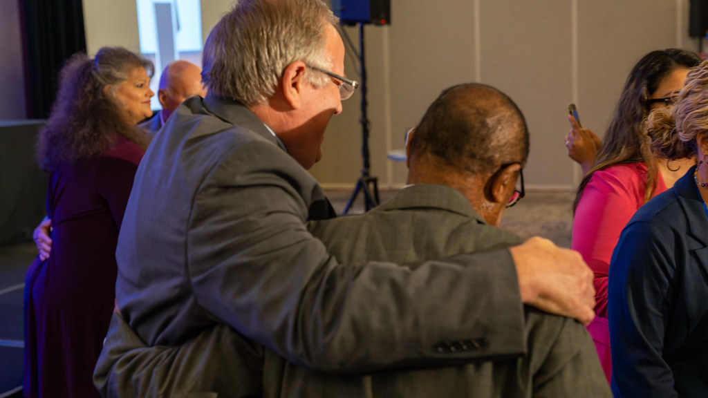 Conference attendees greeting each other with hugs in the lobby