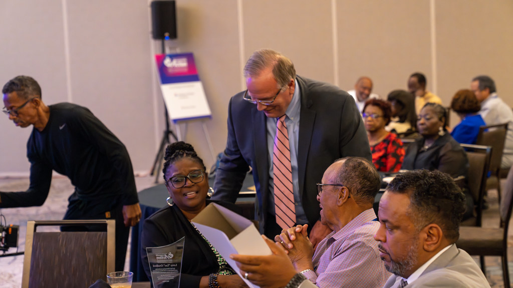 Conference attendees seated at round tables reviewing session materials