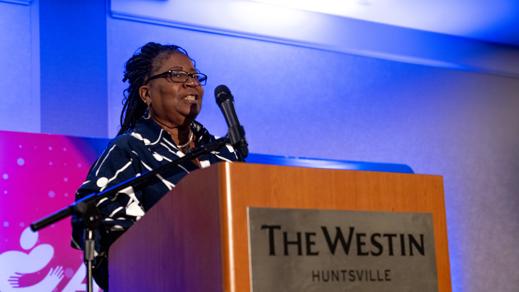 A speaker smiling at the podium during her address