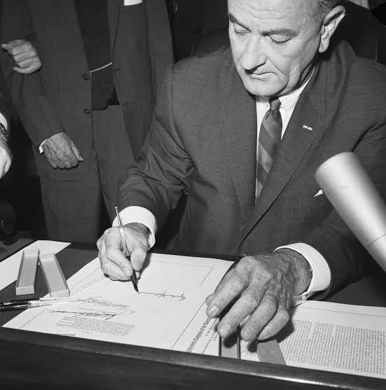 Close-up of President Lyndon B. Johnson signing the Economic Opportunity Act of 1964