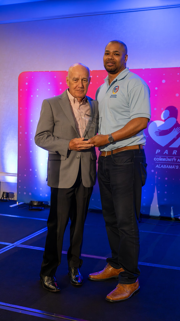 Two smiling men on stage holding an award together