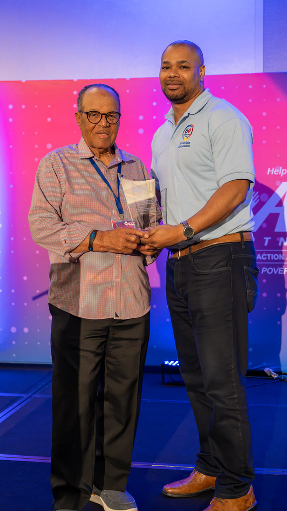 A presenter handing a glass award to a recipient on stage